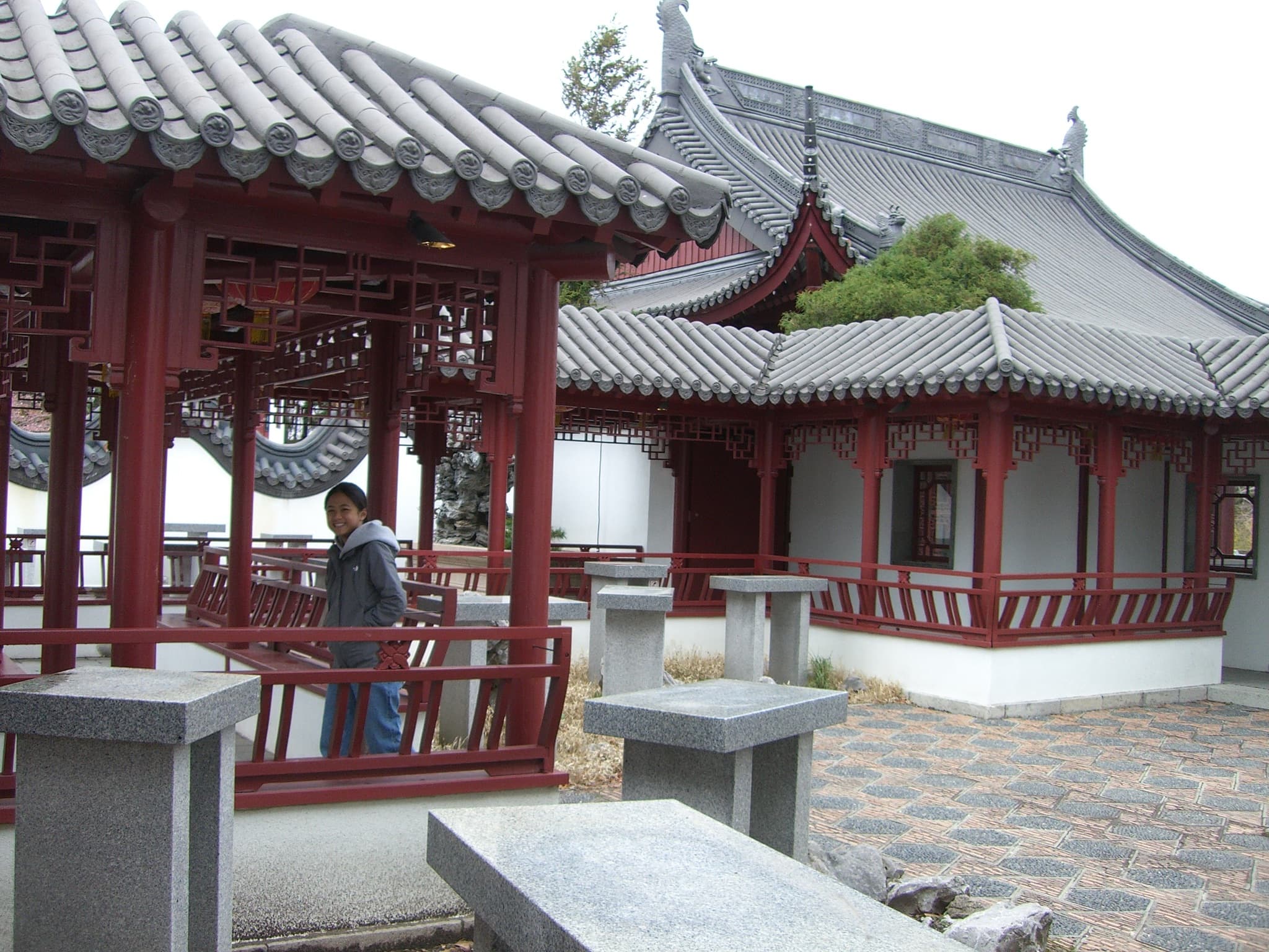 A younger me in a traditional garden courtyard with red pavilions.